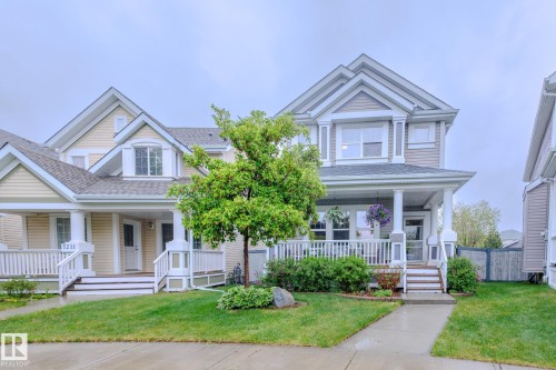 Exterior facade featuring multi-tone siding, a covered porch with white railings, and mature landscaping - 7207 14A Avenue, Edmonton, AB - Outdoor With Deck Patio Veranda With Facade