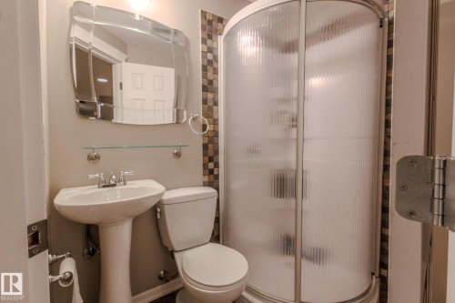 Pedestal sink with chrome faucet, complemented by a decorative mirror and glass shelf - 7207 14A Avenue, Edmonton, AB - Indoor Photo Showing Bathroom