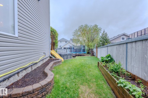 Grassed backyard featuring a stone-block garden bed, wood privacy fence, and a raised planter box - 7207 14A Avenue, Edmonton, AB - Outdoor