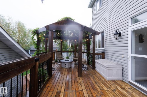 Expansive wood-finish deck featuring a pergola with string lighting, black metal railings, and a built-in hot tub - 7207 14A Avenue, Edmonton, AB - Outdoor With Exterior