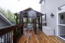 Expansive wood-finish deck featuring a pergola with string lighting, black metal railings, and a built-in hot tub - 7207 14A Avenue, Edmonton, AB  - Outdoor With Exterior 