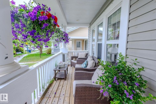 Inviting porch featuring wood-finish flooring, white spindle railing, and a slatted ceiling - 7207 14A Avenue, Edmonton, AB - Outdoor With Deck Patio Veranda With Exterior