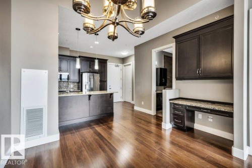 Rich wood-finish flooring extending throughout the open concept space - 607 11080 Ellerslie Road, Edmonton, AB - Indoor Photo Showing Kitchen