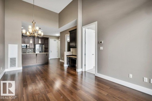 Hardwood-finish flooring extending through an open-concept living area with vaulted ceilings - 607 11080 Ellerslie Road, Edmonton, AB - Indoor
