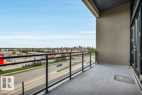 Balcony with concrete flooring and a modern black metal and glass railing - 607 11080 Ellerslie Road, Edmonton, AB - Outdoor With Balcony With View With Exterior