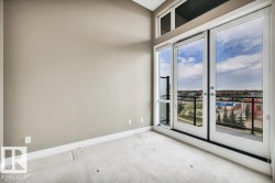 Floor-to-ceiling windows and a glass-paneled sliding door opening to a balcony with black metal railings - 