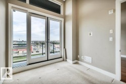 Light-filled room featuring a broad window and glass French door leading to a balcony with black metal railings - 