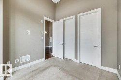 Neutral-toned room featuring a vaulted ceiling, light-colored carpeting, and three white interior doors with contemporary hardware - 