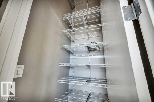 Storage closet featuring adjustable white wire shelving, a light switch, and a white painted door - 607 11080 Ellerslie Road, Edmonton, AB - Indoor With Storage