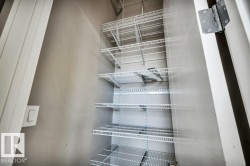 Storage closet featuring adjustable white wire shelving, a light switch, and a white painted door - 