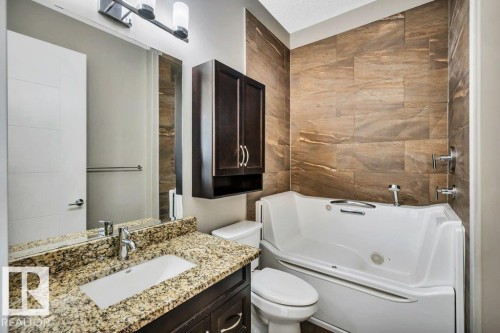 Bathroom featuring a walk-in tub with textured wall tile surround - 607 11080 Ellerslie Road, Edmonton, AB - Indoor Photo Showing Bathroom