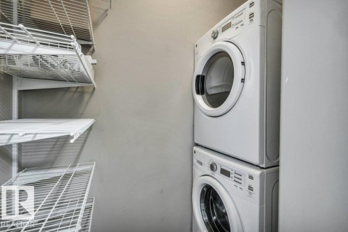 Laundry area featuring a stacked washer and dryer unit, and white wire shelving - 607 11080 Ellerslie Road, Edmonton, AB - Indoor Photo Showing Laundry Room