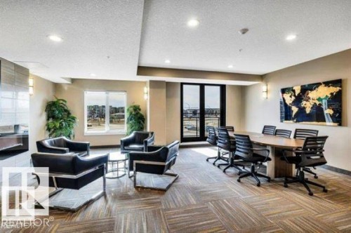 Open-concept common area featuring carpet tile flooring, recessed lighting, and a large window - 607 11080 Ellerslie Road, Edmonton, AB - Indoor