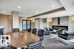Conference room featuring a wood-finish oval table, recessed ceiling lighting, and a modern fireplace with a tiled surround - 