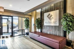 Lobby entrance featuring large glass doors, tile flooring, a built-in upholstered bench, a decorative accent wall, and recessed lighting - 