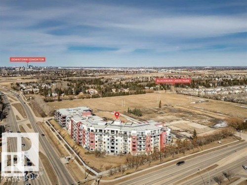 Modern multi-story residential building with white and red exterior accents, featuring multiple balconies - 607 11080 Ellerslie Road, Edmonton, AB - Outdoor With View