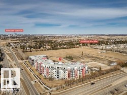 Modern multi-story residential building with white and red exterior accents, featuring multiple balconies - 
