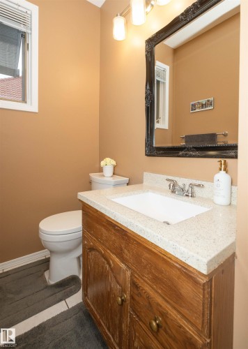 Bathroom vanity featuring a light speckled countertop with an integrated sink and a wood-finish cabinet - 10739 109 Avenue, Westlock, AB 
