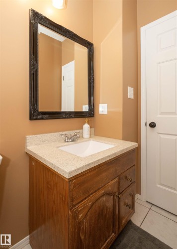 Bathroom vanity featuring a wood-finish cabinet, speckled light-toned countertop, and an undermount sink with a chrome faucet - 10739 109 Avenue, Westlock, AB 