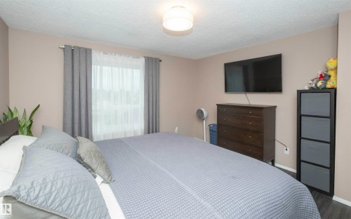 Room featuring wood-finish flooring, neutral wall paint, and a window with curtain rod and sheer white panels - 10739 109 Avenue, Westlock, AB 
