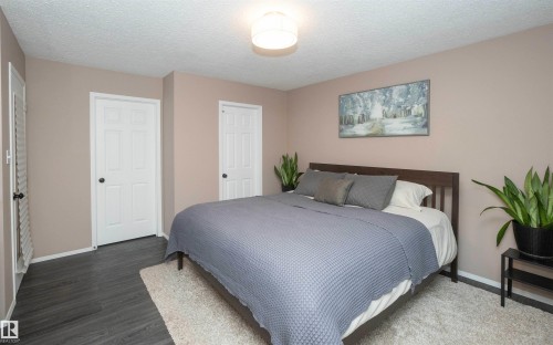 Spacious room featuring dark wood-finish flooring, light tan walls, and a white popcorn ceiling - 10739 109 Avenue, Westlock, AB 