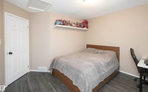 Room featuring neutral painted walls, dark wood-finish flooring, and a white six-panel door with black hardware - 10739 109 Avenue, Westlock, AB 