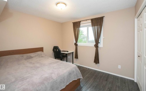 Bedroom featuring neutral-toned walls, wood-finish flooring, a double-paned window, and a built-in closet with bi-fold doors - 10739 109 Avenue, Westlock, AB 