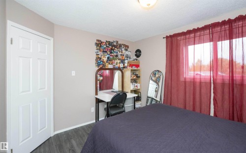Room featuring wood-finish flooring and a white six-panel door - 10739 109 Avenue, Westlock, AB 