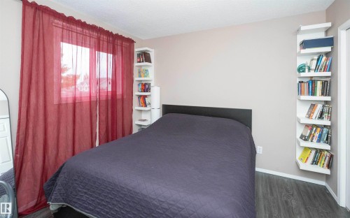 Window with red sheer curtains, wood-finish flooring, and built-in shelving - 10739 109 Avenue, Westlock, AB 