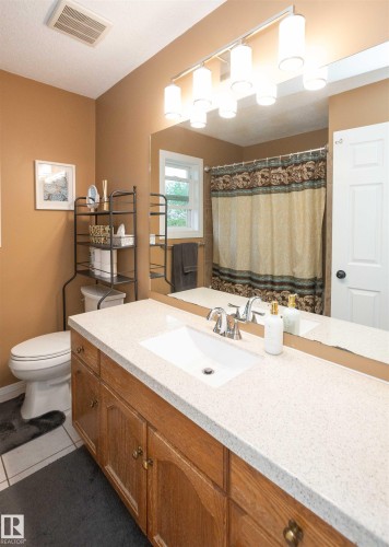 Bathroom featuring a single vanity with wood-finish cabinetry, a white countertop, and an integrated sink - 10739 109 Avenue, Westlock, AB 