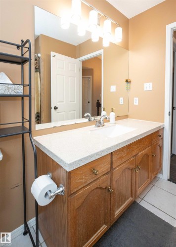 Bathroom vanity featuring a single basin, a speckled countertop, and wood-finish cabinetry with brass hardware - 10739 109 Avenue, Westlock, AB 