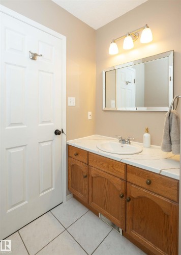 Bathroom vanity featuring an integrated sink, polished chrome faucet, and wood-finish cabinetry - 10739 109 Avenue, Westlock, AB 