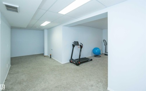 Spacious room featuring light-colored carpeting, white walls, and a drop ceiling with integrated lighting - 10739 109 Avenue, Westlock, AB 