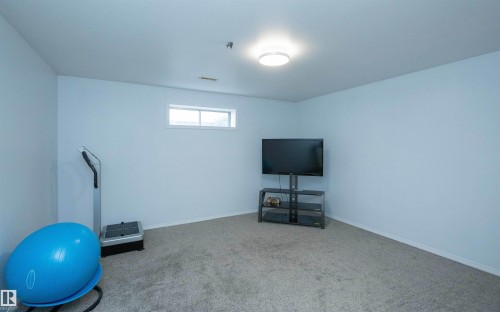 Carpeted room featuring a ceiling-mounted light fixture, light-colored walls, and a horizontal window - 10739 109 Avenue, Westlock, AB 