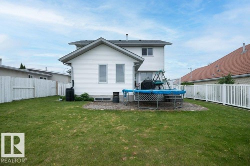 Expansive backyard featuring a manicured lawn, a paver patio, and white privacy fencing - 10739 109 Avenue, Westlock, AB 