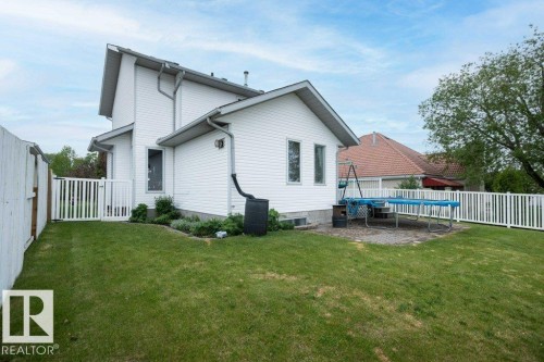 Spacious exterior featuring white vinyl siding, a pitched roof, and a gravel patio area - 10739 109 Avenue, Westlock, AB 
