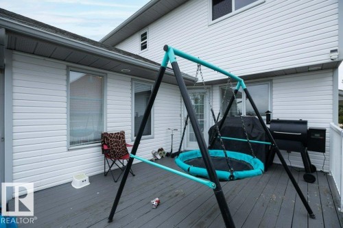 Spacious back deck featuring a weathered wood-finish floor and white railing - 10739 109 Avenue, Westlock, AB 