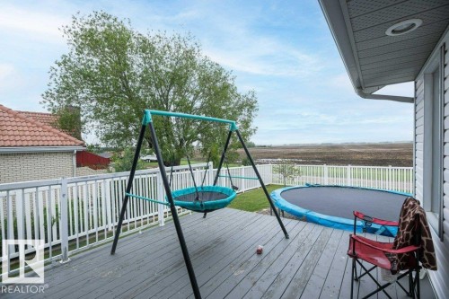 Expansive outdoor deck featuring wood-finish flooring and a white railing system - 10739 109 Avenue, Westlock, AB 