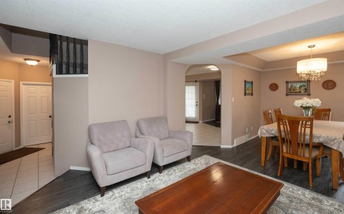 Open-concept living space featuring wood-finish flooring, a recessed ceiling, a decorative chandelier, and an arched doorway - 10739 109 Avenue, Westlock, AB 