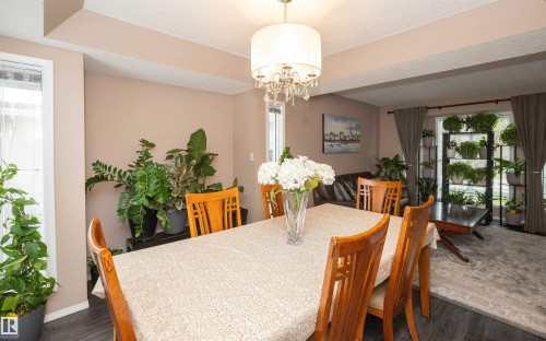 Dining area featuring wood-finish flooring, a contemporary chandelier, and a large window - 10739 109 Avenue, Westlock, AB 