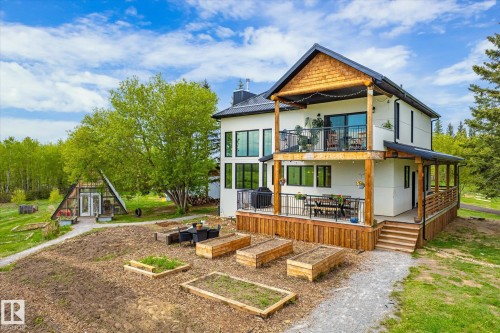 Two-story residence featuring a ground-level deck with wooden railing and a second-story balcony with metal railing - 59102 Rge Road 234, Rural Westlock County, AB 
