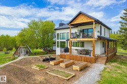 Two-story residence featuring a ground-level deck with wooden railing and a second-story balcony with metal railing - 