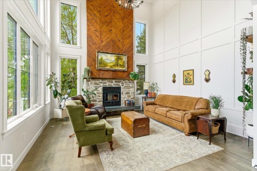 Two-story living area featuring a stone fireplace with a herringbone wood-finish accent wall - 59102 Rge Road 234, Rural Westlock County, AB 