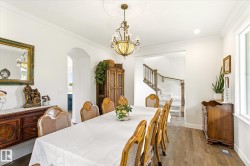 Formal dining space featuring wood-finish flooring, a decorative chandelier with a ceiling medallion, and white crown molding - 