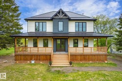 Contemporary two-story residence featuring a dark metal roof, white and charcoal siding, and black-framed windows - 