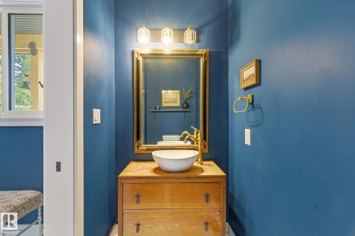 Powder room featuring a vessel sink with a gold-finish faucet, a gold-framed mirror, and a three-light vanity fixture - 59102 Rge Road 234, Rural Westlock County, AB 