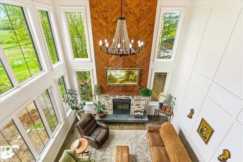 Vaulted living space with a floor-to-ceiling stone fireplace and wood-finish accent wall - 59102 Rge Road 234, Rural Westlock County, AB 