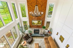 Vaulted living space with a floor-to-ceiling stone fireplace and wood-finish accent wall - 