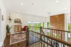 Upper-level hallway featuring wood-finish flooring, recessed lighting, and a wood and metal railing system - 