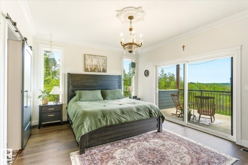 Spacious bedroom featuring wood-finish flooring, a decorative chandelier, and a barn door entry - 59102 Rge Road 234, Rural Westlock County, AB 